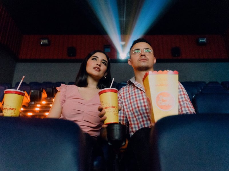 2 people sitting in a movie theater, facing the screen that is out of view